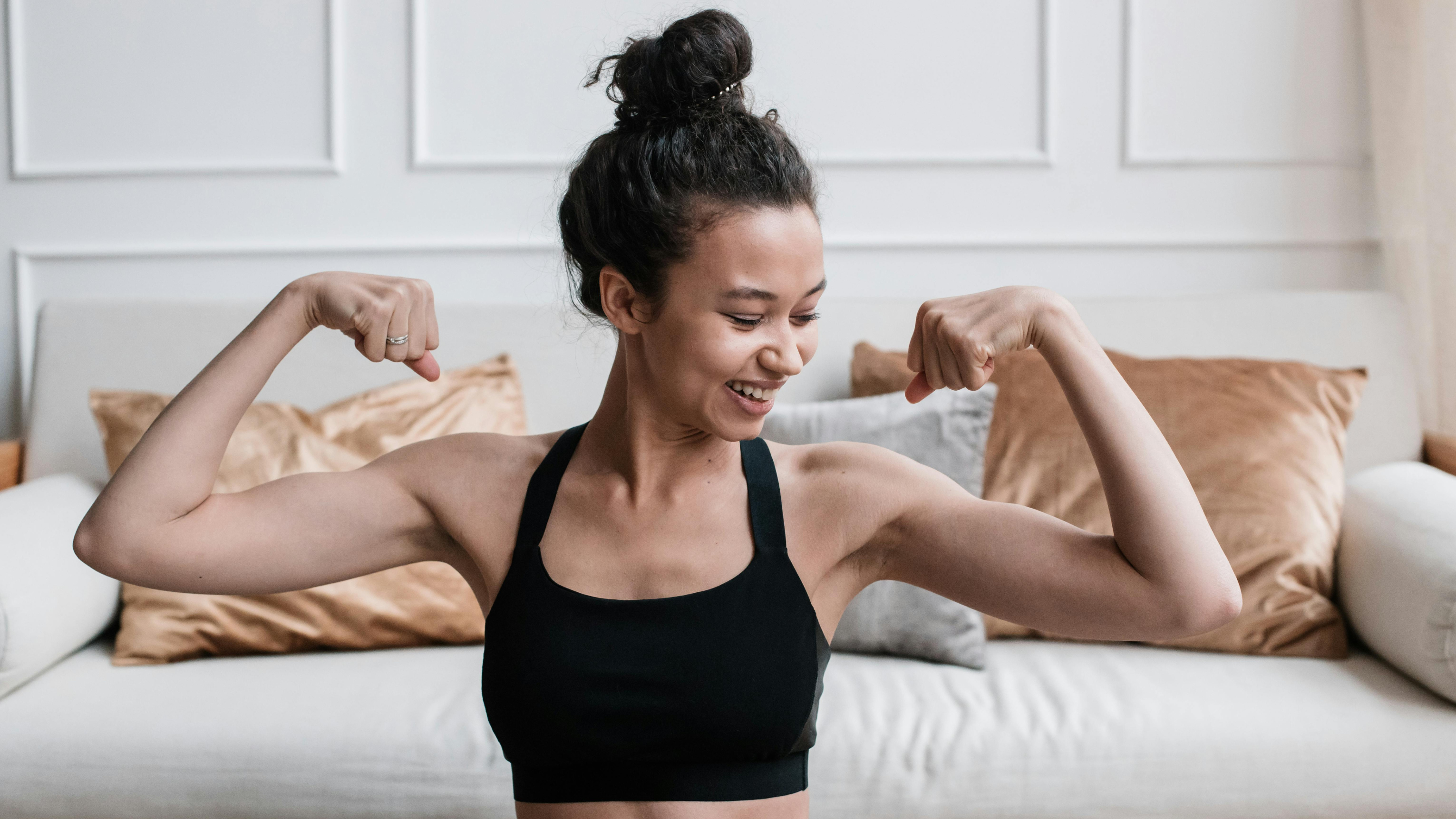 Woman flexing her muscles in a living room setting